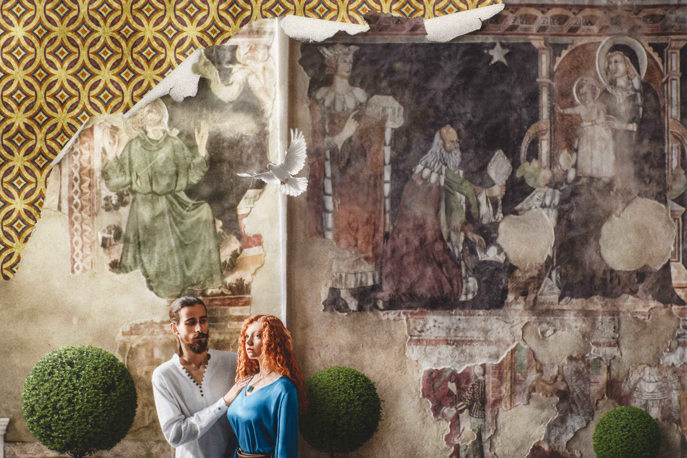 The couple stands in front of ancient medieval frescoes depicting a scene from the Bible. A white dove flies over the two of them. The couple is shown from a print on tattered fibre photographic paper, under which a medieval pattern is revealed.